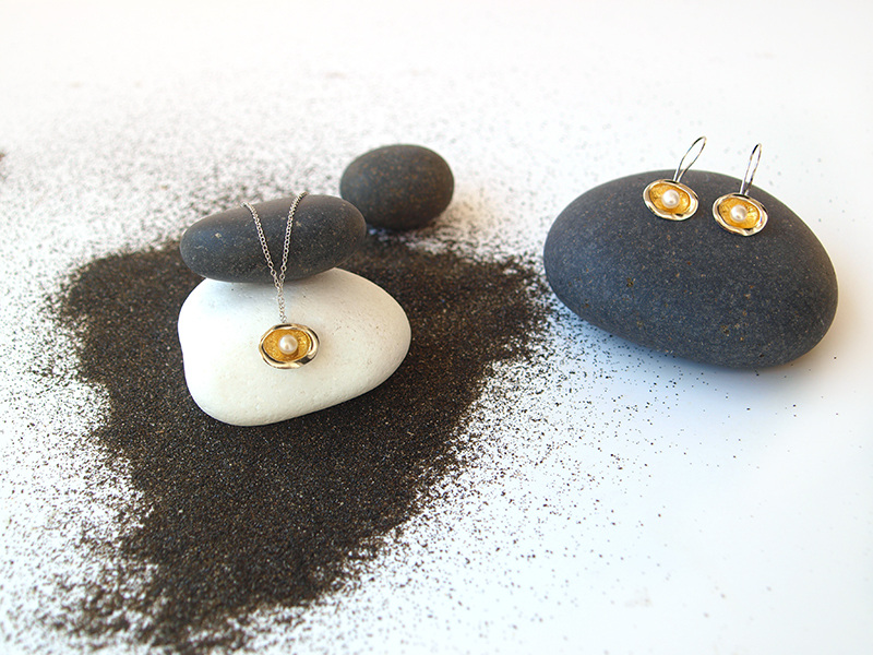 jewellery placed on black soil and black and white rocks